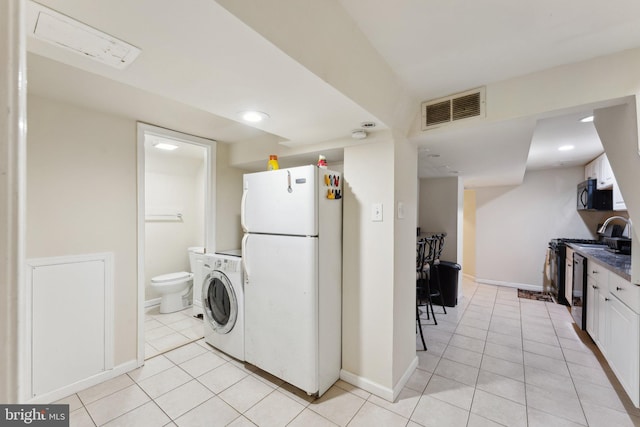 kitchen featuring stainless steel electric range oven, washer / clothes dryer, light tile patterned floors, white fridge, and white cabinetry