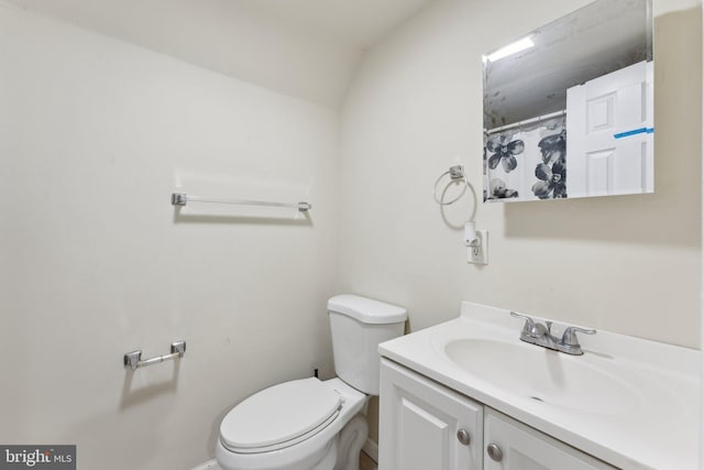 bathroom featuring vanity, toilet, and vaulted ceiling