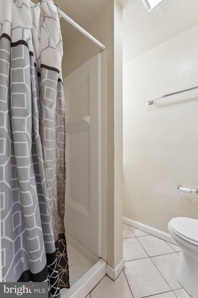 bathroom with toilet, tile patterned floors, and walk in shower