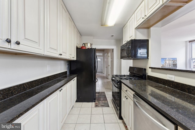 kitchen featuring light tile patterned floors, white cabinetry, dark stone counters, and black appliances