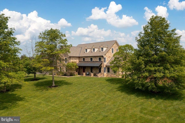 rear view of property featuring stone siding, a standing seam roof, metal roof, and a yard