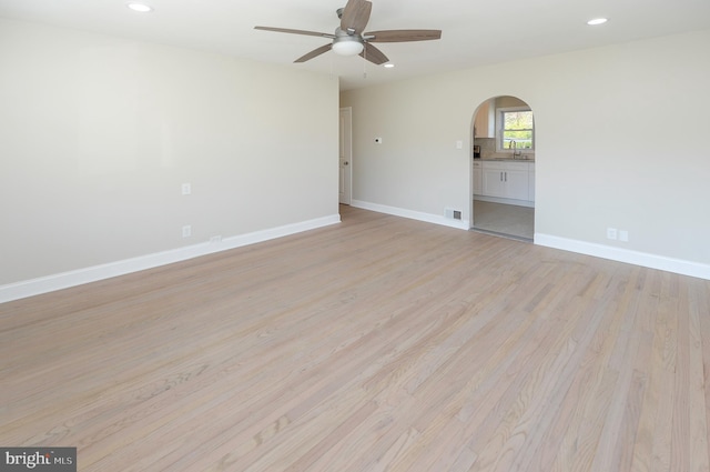 unfurnished room featuring ceiling fan, sink, and light wood-type flooring