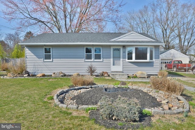 view of front facade featuring entry steps, a shingled roof, and a front lawn