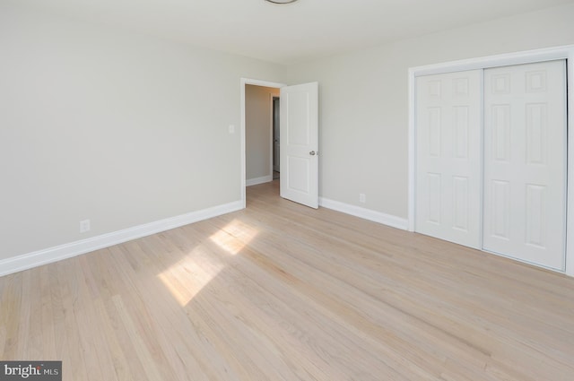 unfurnished bedroom with light wood-type flooring and a closet