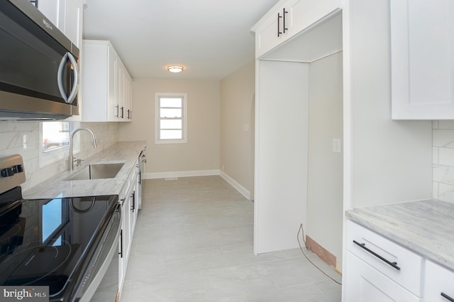 kitchen featuring appliances with stainless steel finishes, sink, decorative backsplash, white cabinetry, and light stone counters