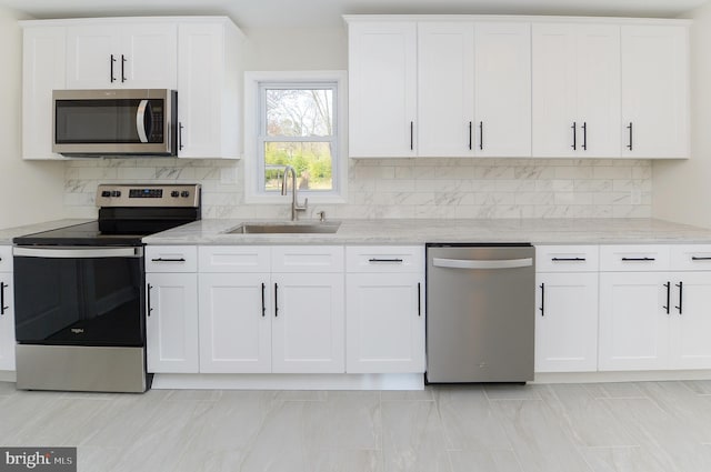 kitchen with backsplash, sink, light stone countertops, appliances with stainless steel finishes, and white cabinets