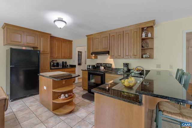 kitchen with black appliances, a breakfast bar, kitchen peninsula, a center island, and dark stone counters