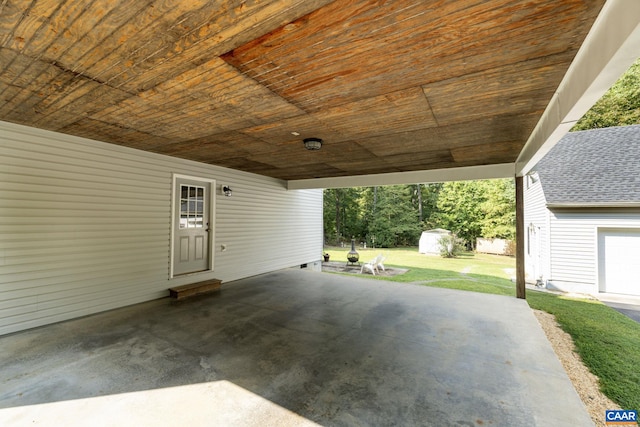 garage with wood ceiling, a yard, a carport, and wooden walls