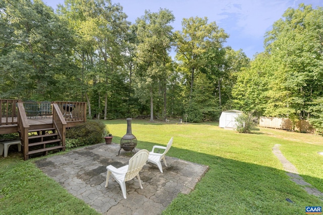 view of yard with a fire pit, a shed, a patio, and a deck