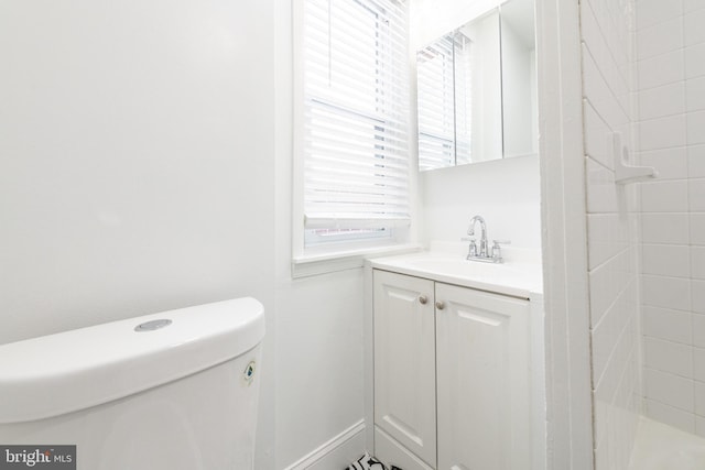 bathroom featuring vanity, a tile shower, and toilet