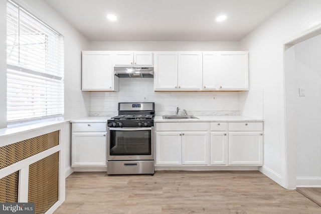 kitchen with stainless steel range with gas stovetop, sink, white cabinetry, and light hardwood / wood-style floors