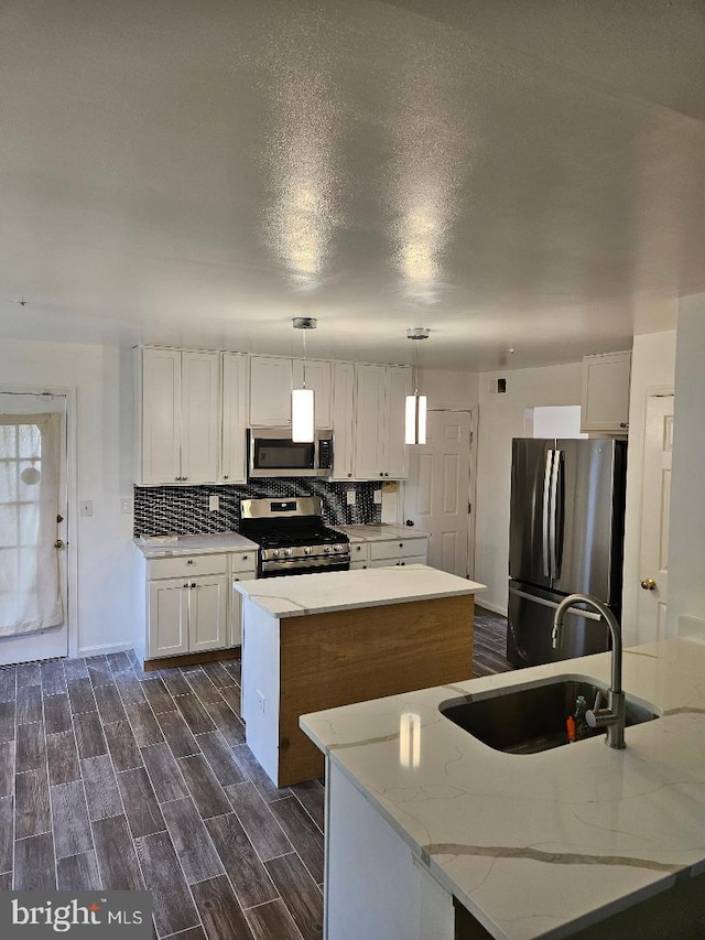 kitchen with a kitchen island, decorative light fixtures, dark wood-type flooring, stainless steel appliances, and sink