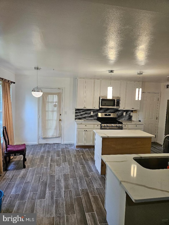 kitchen with dark hardwood / wood-style flooring, hanging light fixtures, stainless steel appliances, sink, and white cabinetry