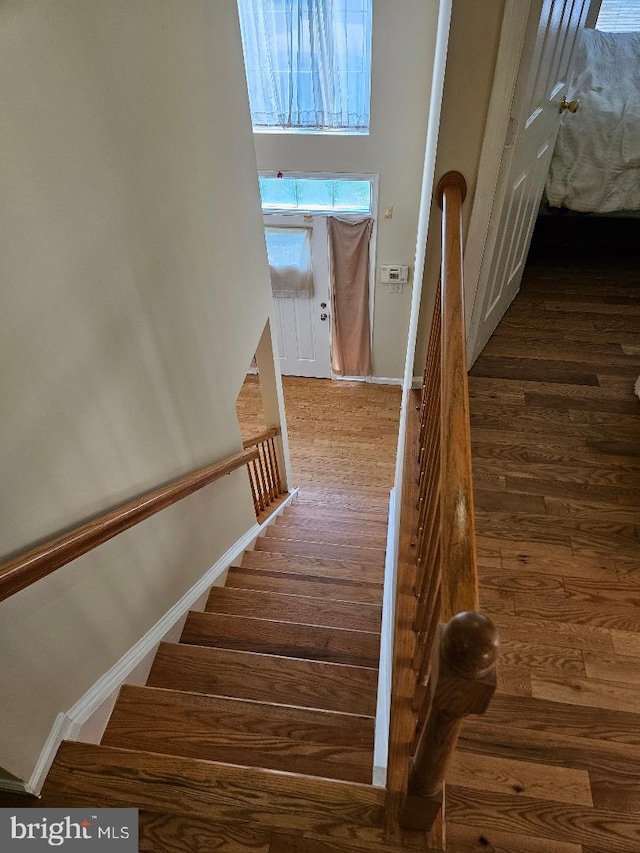 stairway with a towering ceiling and hardwood / wood-style flooring