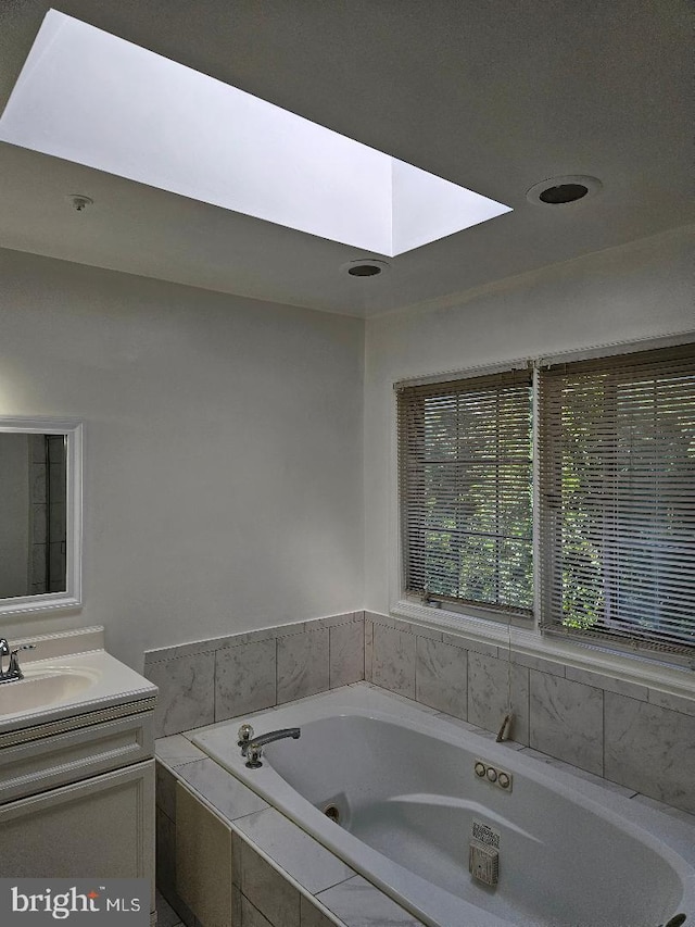 bathroom featuring tiled tub and vanity