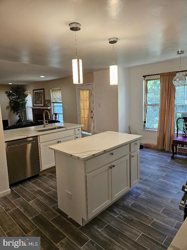 kitchen featuring decorative light fixtures, dishwasher, a center island, and sink