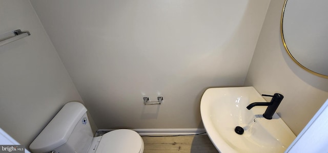 bathroom featuring toilet, wood-type flooring, and sink