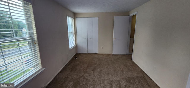 unfurnished bedroom with multiple windows, a textured ceiling, and carpet flooring