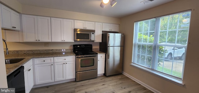 kitchen featuring white cabinetry, stainless steel appliances, light wood-type flooring, and stone counters