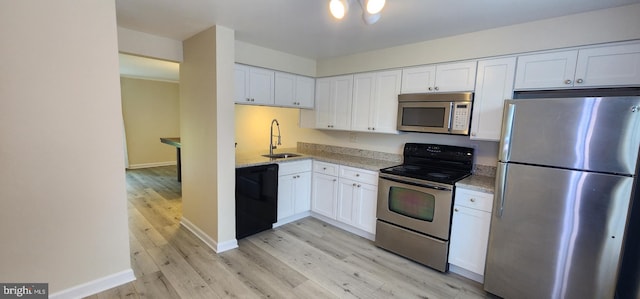 kitchen featuring white cabinets, light stone countertops, stainless steel appliances, and sink