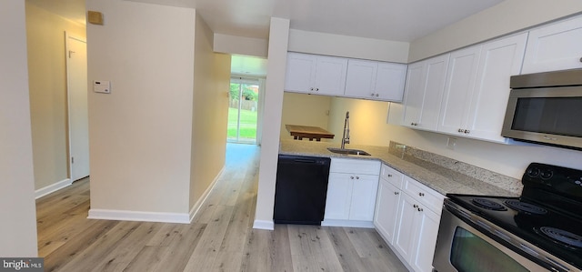 kitchen featuring light wood-type flooring, black appliances, light stone counters, sink, and white cabinets