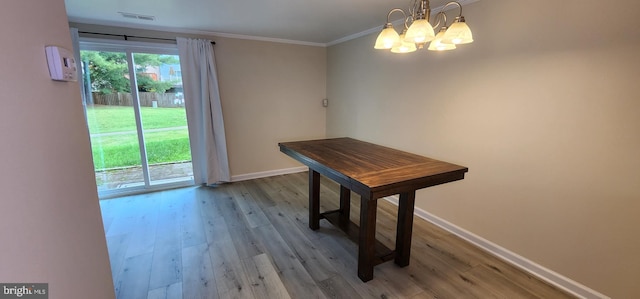 dining area featuring light wood-type flooring, a chandelier, and crown molding