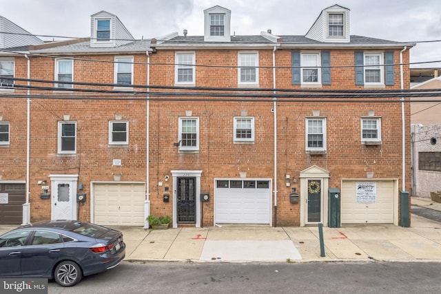 multi unit property featuring a garage, driveway, and brick siding