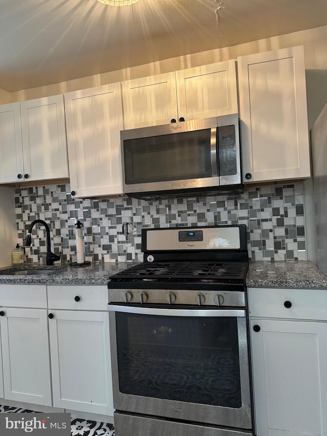 kitchen with sink, stainless steel appliances, white cabinets, and decorative backsplash