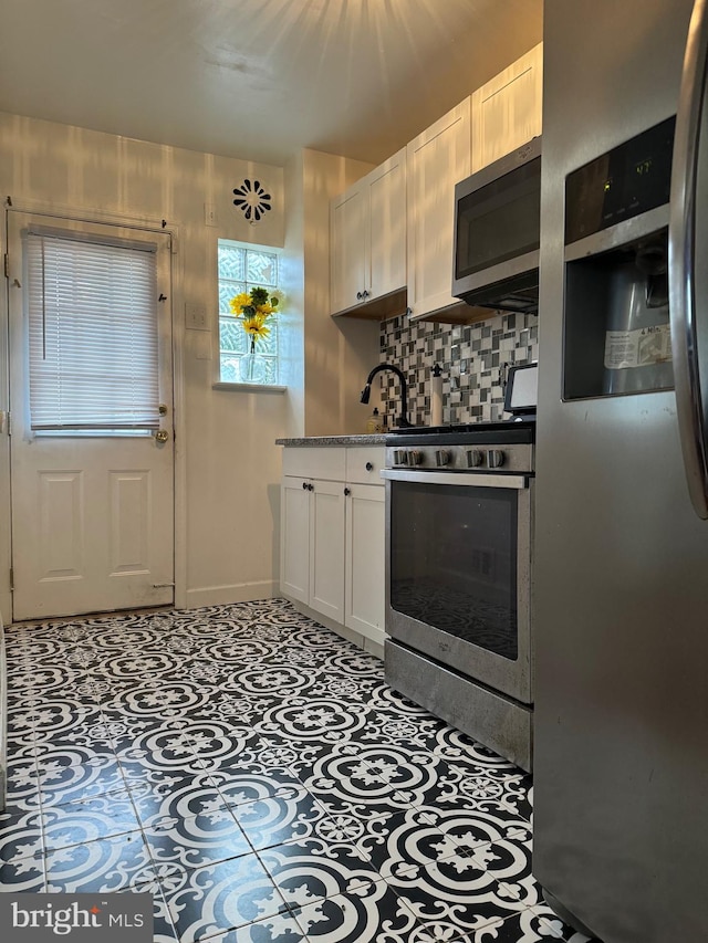 kitchen featuring appliances with stainless steel finishes, tasteful backsplash, light tile patterned floors, and white cabinets