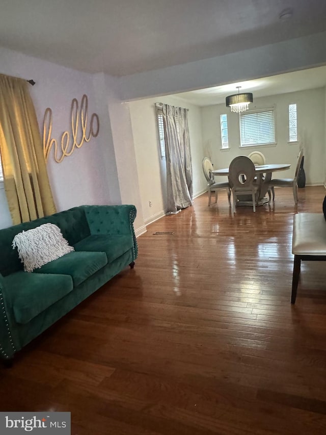 living room with dark wood-type flooring and a chandelier