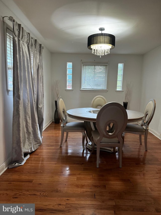 dining room with dark wood-type flooring and a chandelier