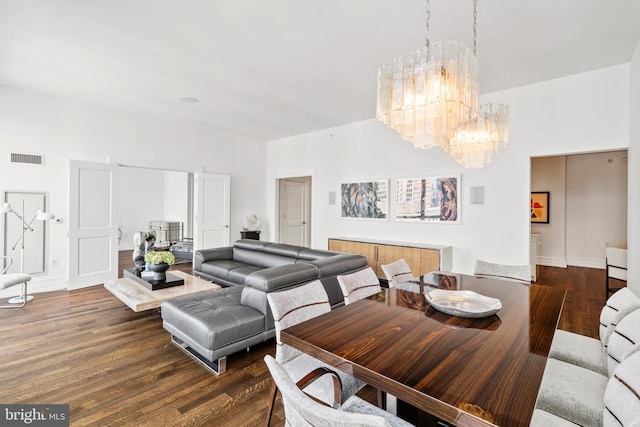 dining area with dark wood-type flooring and an inviting chandelier