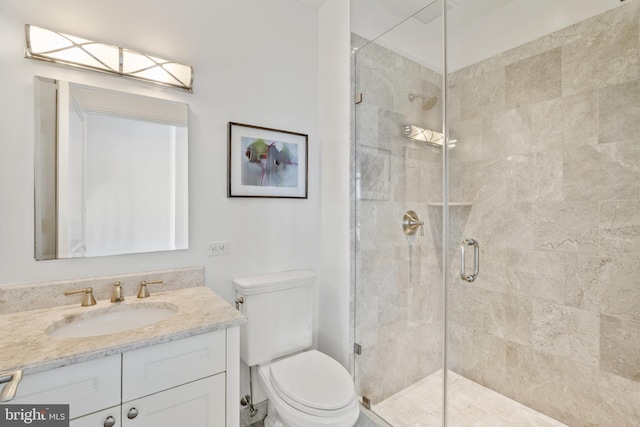 bathroom featuring a shower with door, vanity, and toilet