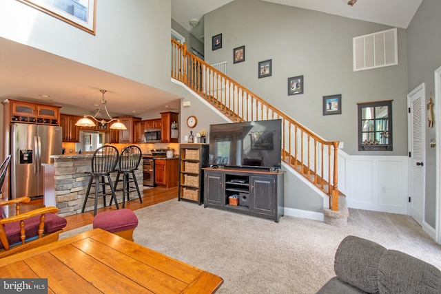 living room with a high ceiling, bar area, and light carpet