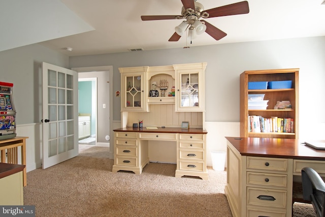 office featuring visible vents, light colored carpet, built in desk, and ceiling fan