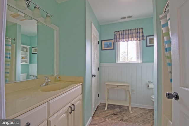 full bath featuring visible vents, toilet, wood finished floors, and wainscoting