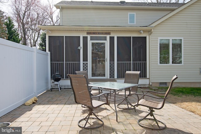 view of patio / terrace featuring outdoor dining area, fence, and a sunroom