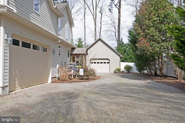 view of side of property featuring a garage, gravel driveway, and central AC unit