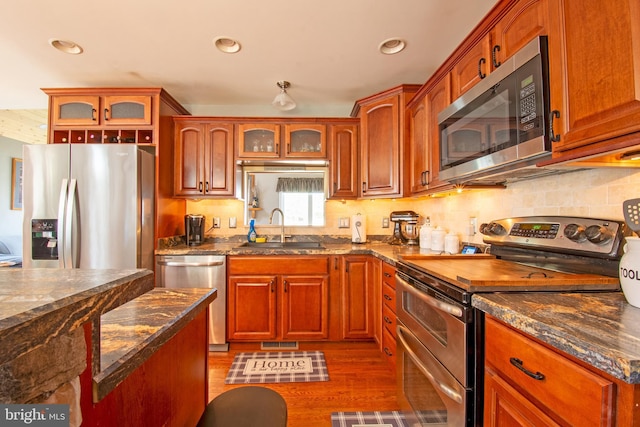 kitchen featuring visible vents, a sink, decorative backsplash, stainless steel appliances, and glass insert cabinets