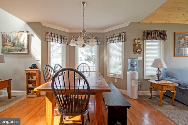 dining space with a notable chandelier, plenty of natural light, light wood-style flooring, and ornamental molding