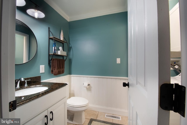 half bathroom with vanity, visible vents, a wainscoted wall, crown molding, and toilet