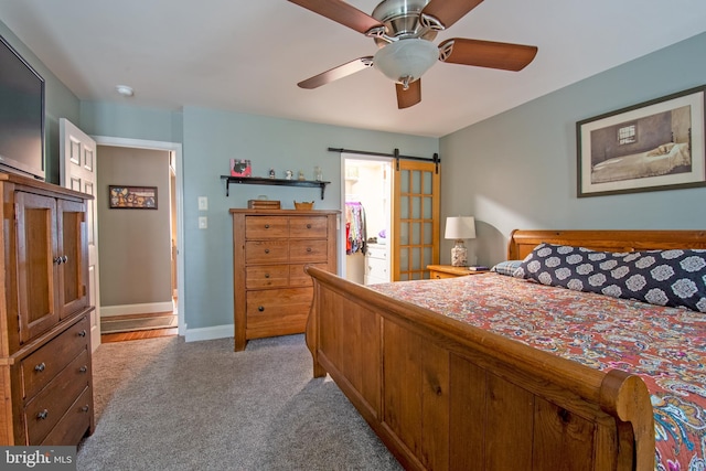 carpeted bedroom featuring a barn door, baseboards, and ceiling fan