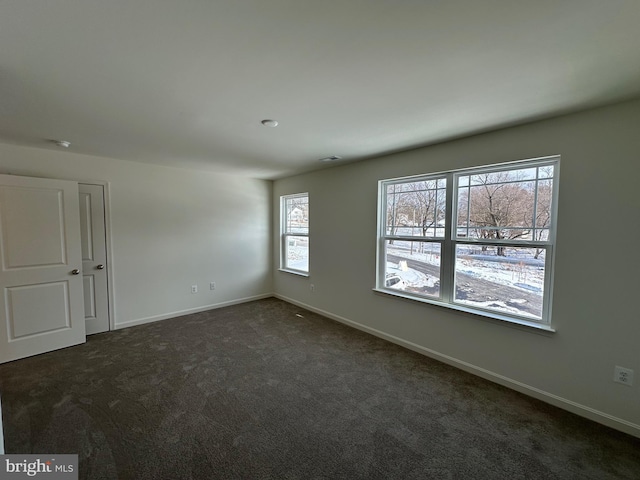 spare room featuring dark carpet