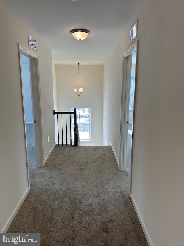 hall with an inviting chandelier and carpet