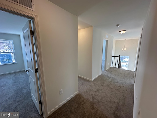 corridor with a wealth of natural light and dark colored carpet