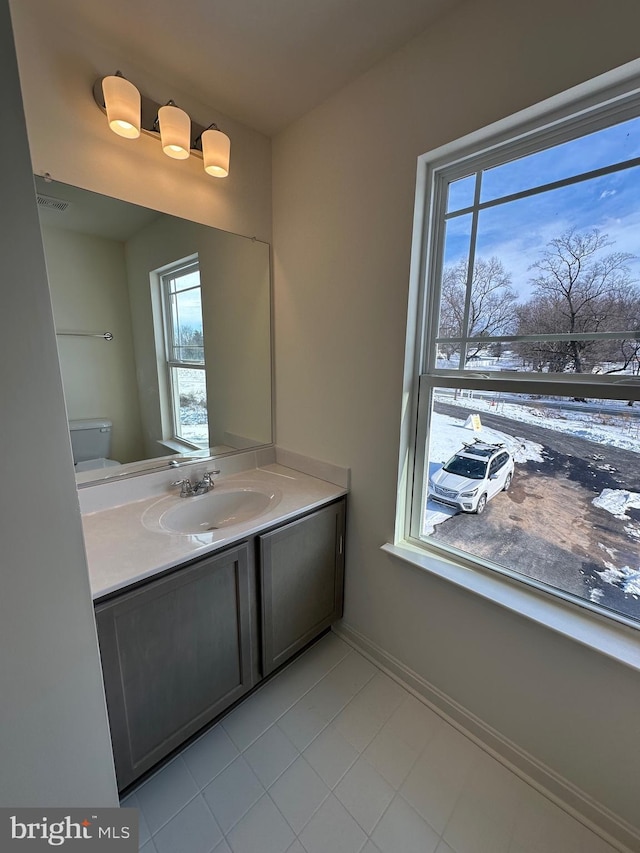 bathroom featuring vanity, a wealth of natural light, tile patterned floors, and toilet