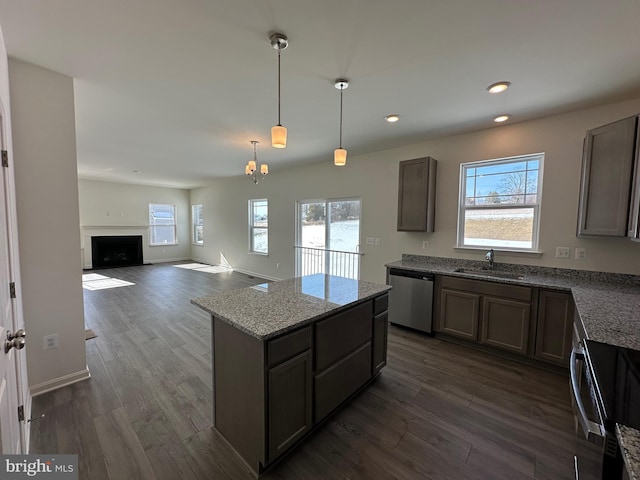 kitchen with pendant lighting, sink, dishwasher, electric range oven, and light stone countertops