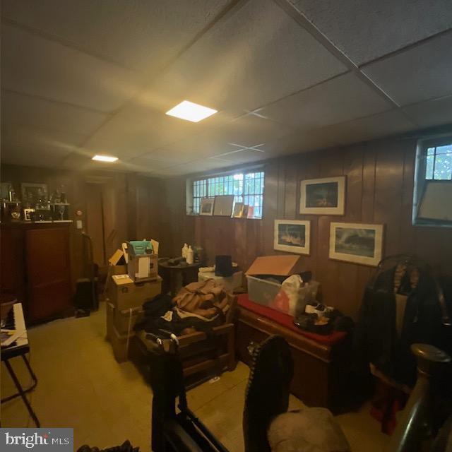 interior space with a paneled ceiling, a healthy amount of sunlight, and wood walls