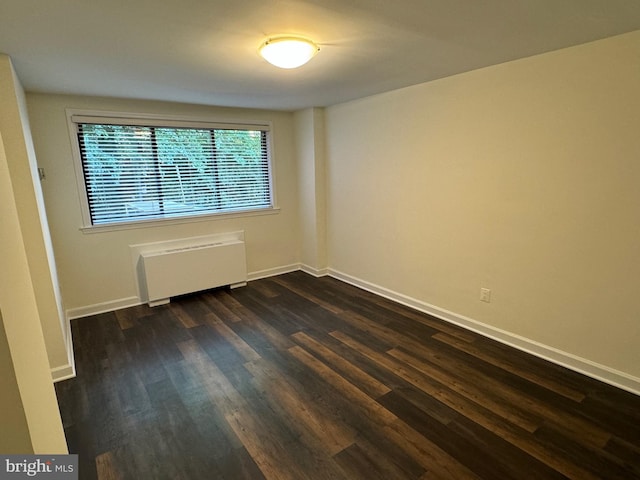 unfurnished room featuring radiator and dark hardwood / wood-style flooring