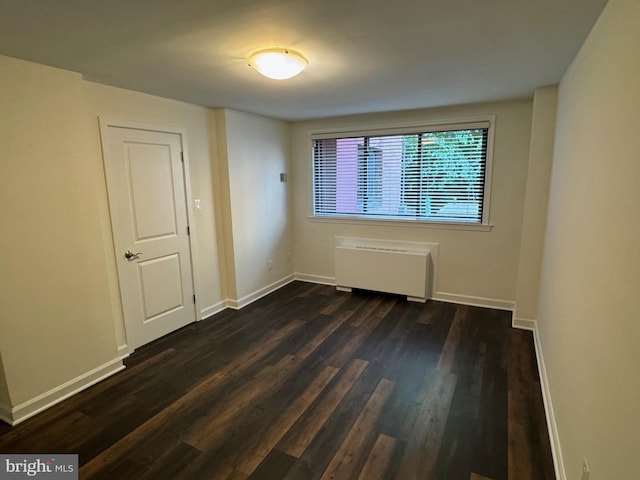 spare room featuring dark wood-type flooring and radiator heating unit